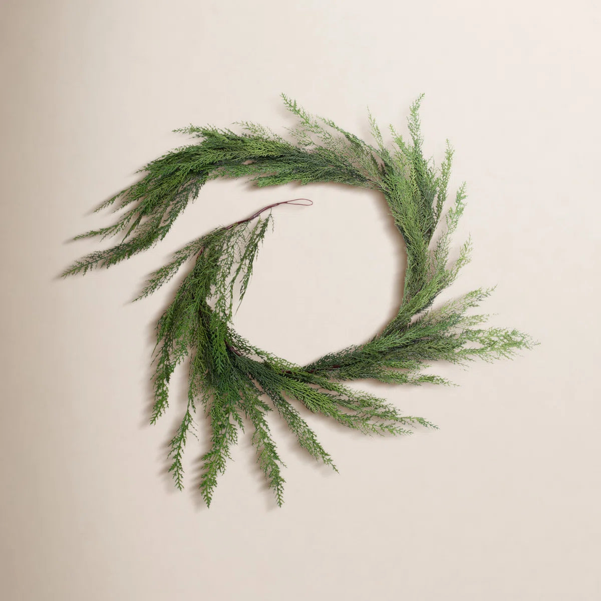 Cedar Christmas garland coiled on a warm wall