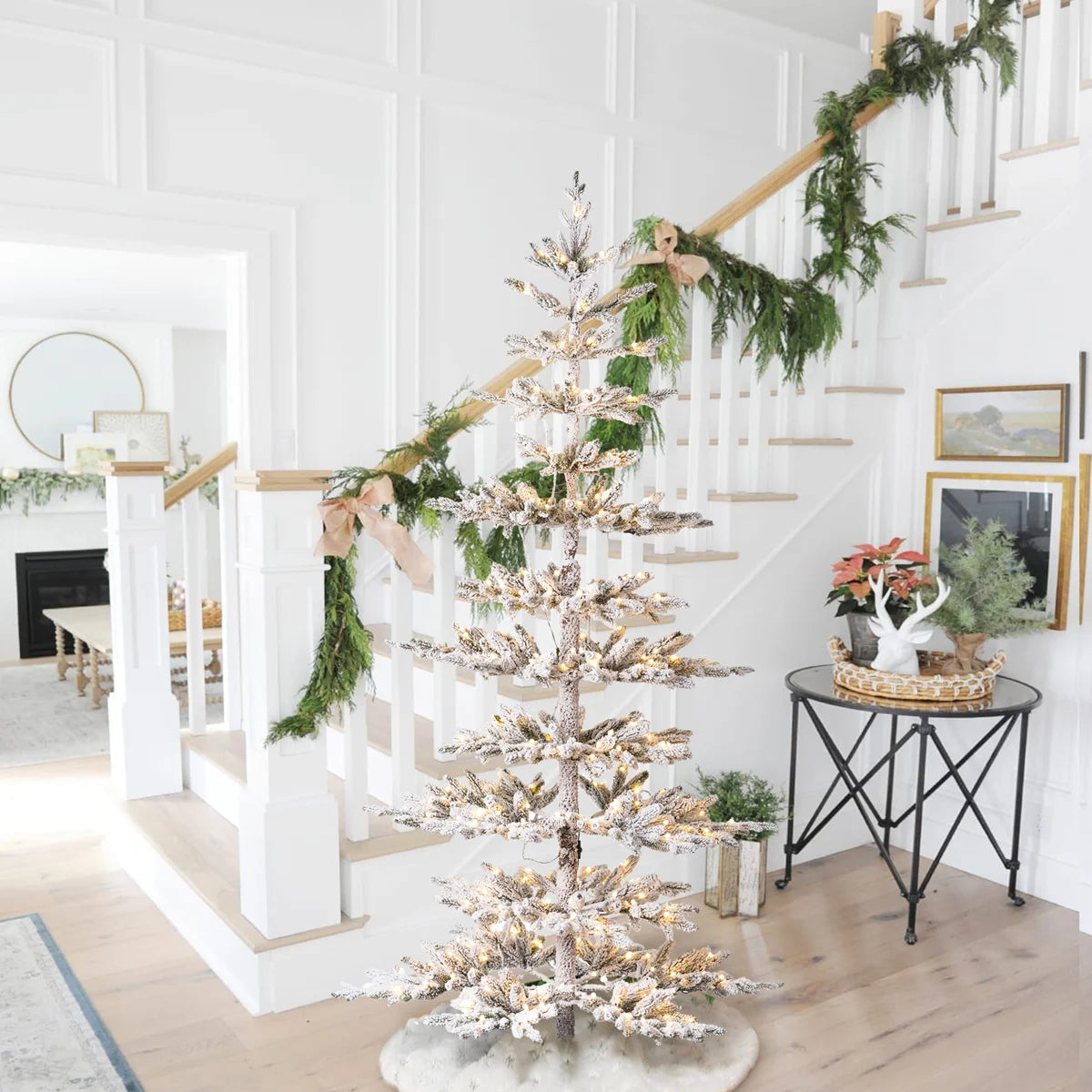 Johvan frosted pine tree in a bright entry with a staircase