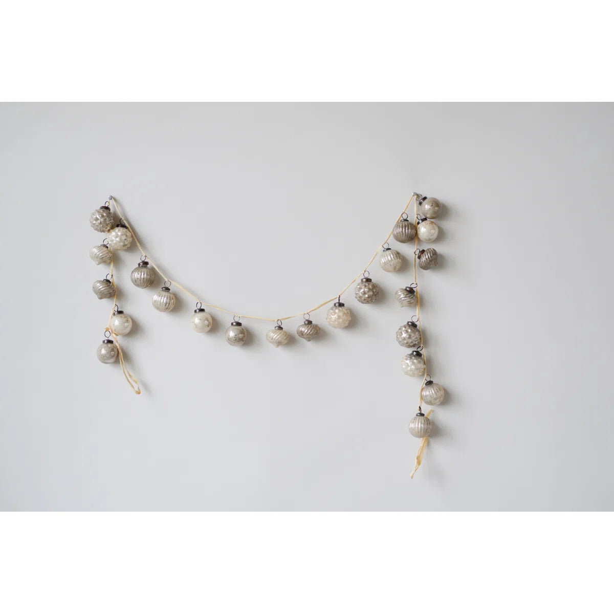 Mercury glass ornament garland draped on a wall