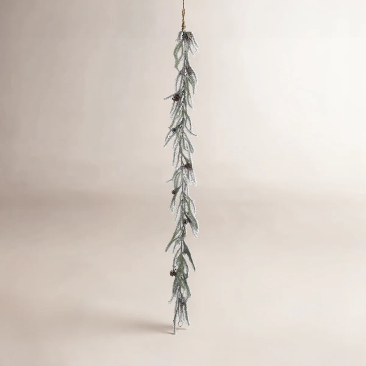 Frosted pine cone garland hanging on a warm wall
