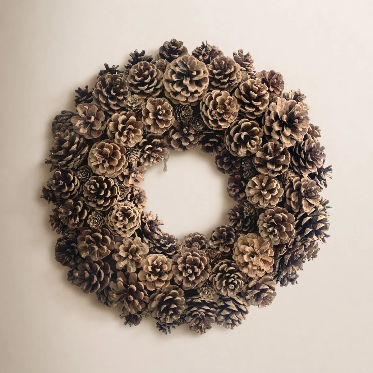 Natural pine cone wreath on a warm wall