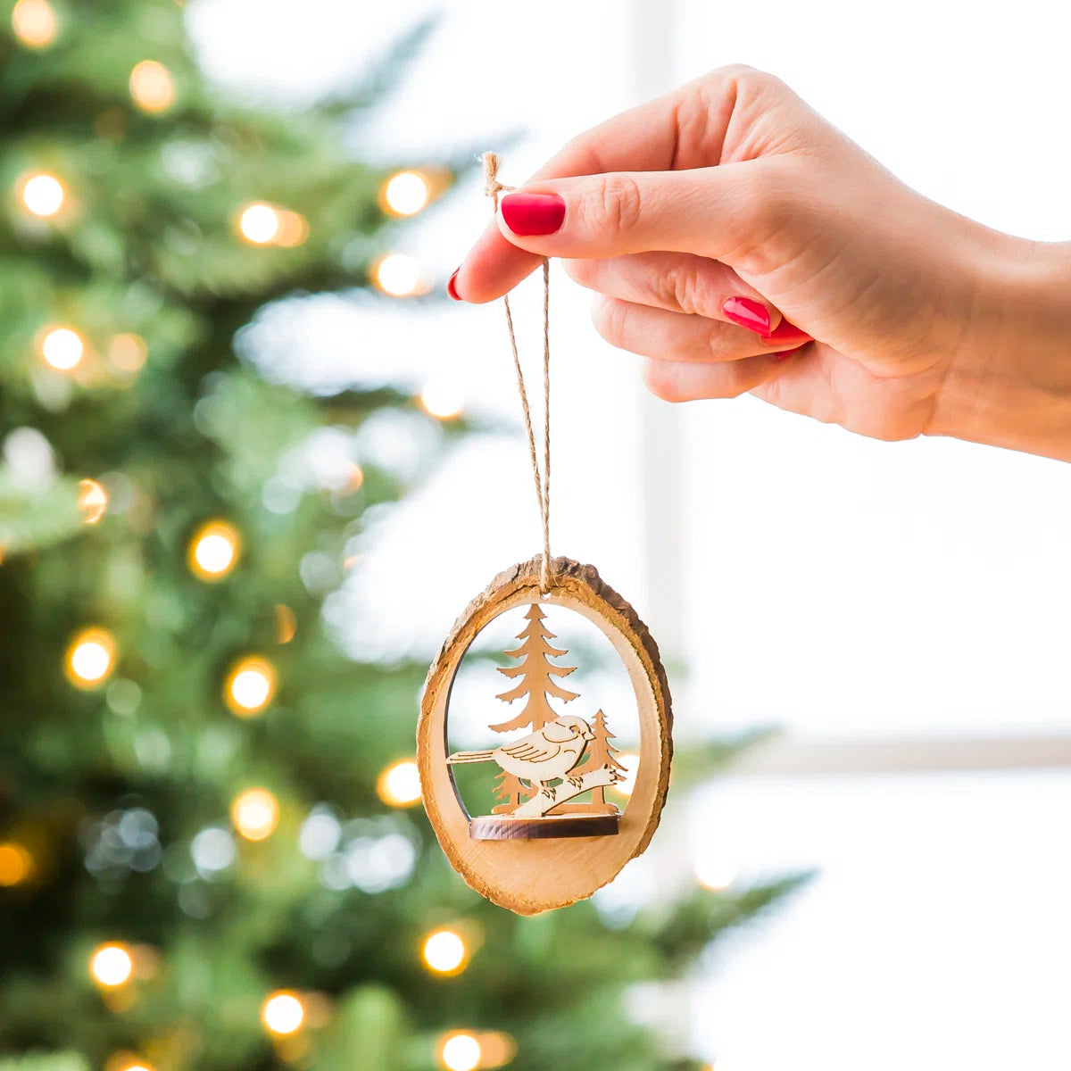 Wood slice ornament hanging on a lit Christmas tree